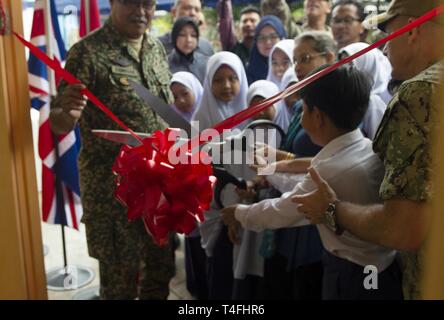 Malaysia (April 11, 2019) – Students observe as U.S. Ambassador to Malaysia, Kamala Lakhdhir cuts the ribbon at Sambir Elementary School. The event marked the successful completion of a project to enclose the ground floor of a building at the school. Pacific Partnership, now in its 14th iteration, is the largest annual multinational humanitarian assistance and disaster relief preparedness mission conducted in the Indo-Pacific. Each year the mission team works collectively with host and partner nations to enhance regional interoperability and disaster response capabilities, increase security an Stock Photo