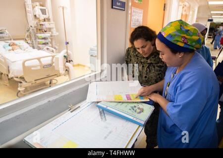 KUCHING, Malaysia (April 11, 2019) – Dr. Shirley Enau shows U.S. Navy Cdr. Brooke Basford treatment procedures for a pediatric patient during a subject matter expert exchange at Sarawak General Hospital as part of Pacific Partnership 2019. Pacific Partnership, now in its 14th iteration, is the largest annual multinational humanitarian assistance and disaster relief preparedness mission conducted in the Indo-Pacific. Each year the mission team works collectively with host and partner nations to enhance regional interoperability and disaster response capabilities, increase security and stability Stock Photo