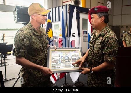 KUCHING, Malaysia (April 11, 2019) – Malaysian Army Lt. Gen. Datuk Suhaimi bin Haji Mohd Zuki, Malaysian Armed Forces joint commander, presents a gift to U.S. Navy Capt. Randy Van Rossum, Pacific Partnership 2019 mission commander, during the Pacific Partnership 2019 closing ceremony in Malaysia. Pacific Partnership, now in its 14th iteration, is the largest annual multinational humanitarian assistance and disaster relief preparedness mission conducted in the Indo-Pacific. Each year the mission team works collectively with host and partner nations to enhance regional interoperability and disas Stock Photo