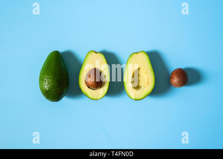 Avocado with half and seed on light blue background. Hard light Stock Photo