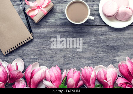 Morning cup of coffee with milk, cake macaron, gift or present box and magnolia flowers on rustic wooden table. flat lay. top view. spring holiday bre Stock Photo