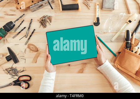Female carpenter using digital tablet computer in woodwork workshop, blank mock up screen of modern device Stock Photo