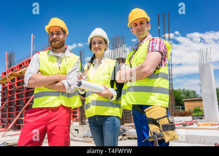 Portrait of three confident and reliable young employees at construction site Stock Photo