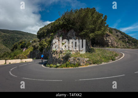 Dramatic view of a cyclist on a road bike cycling a hairpin bend in the Parque Rural de Anaga park, TF-12 Tenerife, Spain Stock Photo