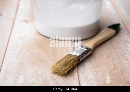 Brushes and cans with white paint on the boards. Preparation for painting boards. Side view. Stock Photo