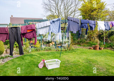Clothes hang out to dry on a washing line in a residential back garden in the spring. Stock Photo