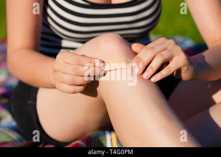 Woman applying bandage on knee Stock Photo