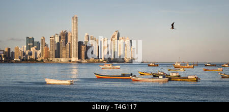 Idyllic urban scene with skyscrapers in the background, small boats floating on the water and flying bird at sunset time Stock Photo