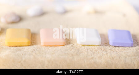 Four solid pieces of soap lie on a pale brown towel. Sea shells in the back. Side view with beautiful light. Stock Photo