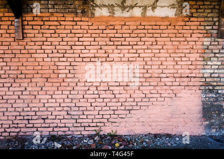 Yellow brick wall, part painted in pink, background with a ground Stock Photo