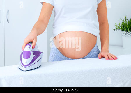 Closeup shot of pregnant woman ironing Stock Photo