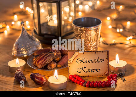 Greeting card Ramadan Kareem with dates, rosary, and metal water cup with Allah text in arabic Stock Photo