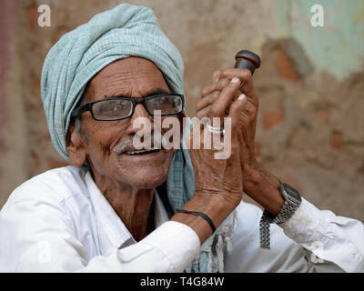 Old Indian Rajasthani man smokes tobacco in his chillum pipe. Stock Photo