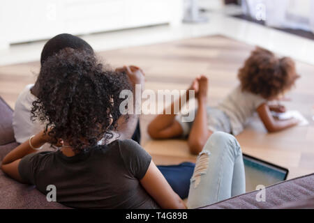 Rear view African American parents using laptop while child playing Stock Photo
