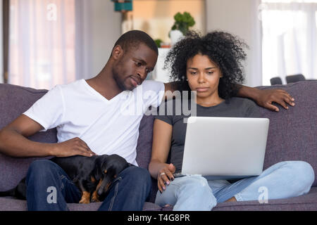 Serious African American man and woman using laptop at home Stock Photo