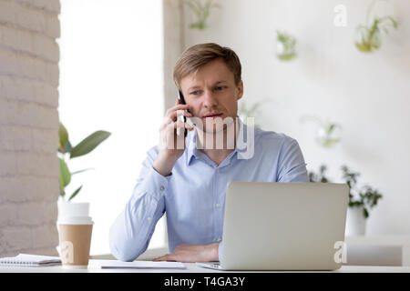Businessman sitting indoors and talking by mobile phone. Stock Photo
