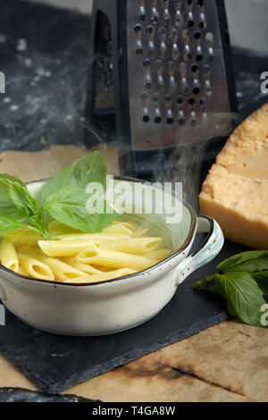 Pasta with green herbs in copper saucepan. Grey stone background. Stock Photo