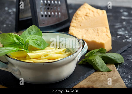 Pasta with green herbs in copper saucepan. Grey stone background. Stock Photo