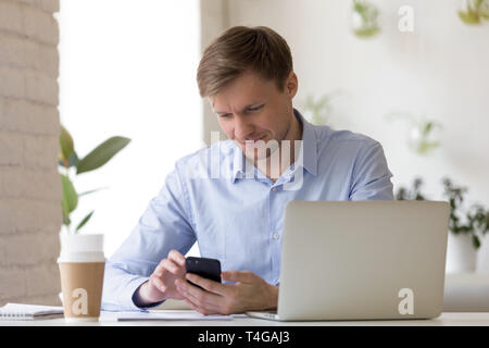 Smiling businessman using smartphone in his workplace Stock Photo