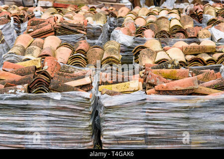 Stacked weathered red roof tiles on ground Stock Photo