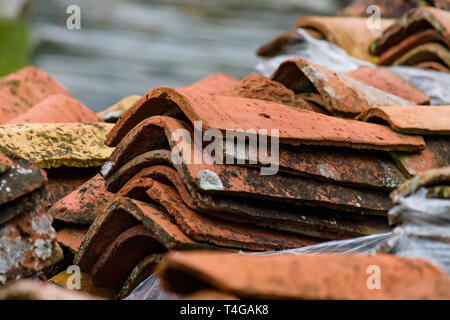 Stacked weathered red roof tiles on ground Stock Photo