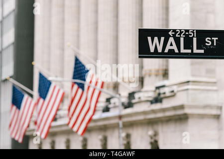 Wall Street sign post with American national flags in background. New York city financial economy district, stock market trade and exchange concept Stock Photo