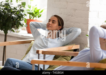 Beautiful woman relaxing on chair at work with colleague Stock Photo