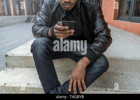 Close up of dark-skinned man looking at mobile phone screen. Stock Photo