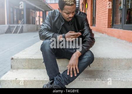 Close up of dark-skinned man looking at mobile phone screen. Stock Photo