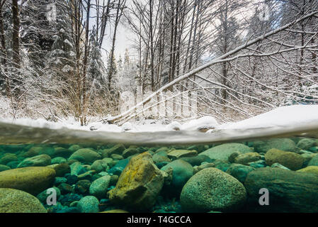 Winter Underwater Split Level Image of Lynn Creek with snow and blue water in the winter in North Vancouver, Canada. Stock Photo