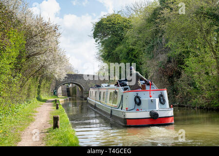 Canal boat heading towards a bridge and lock on the oxford canal on a spring morning. Near Enslow, Oxfordshire, England
