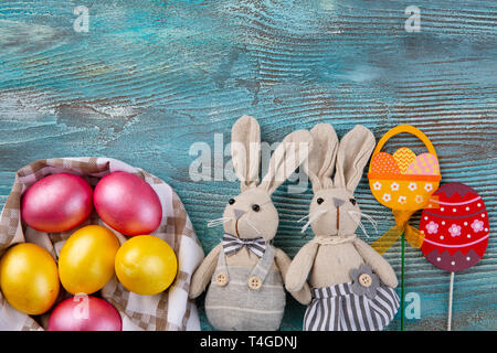 Fluffy foxy rabbits with Easter eggs on blue wooden background. Copy space Stock Photo