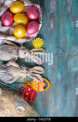 Fluffy foxy rabbits with Easter eggs on blue wooden background. Copy space Stock Photo