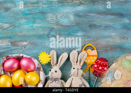 Fluffy foxy rabbits with Easter eggs on blue wooden background. Copy space Stock Photo