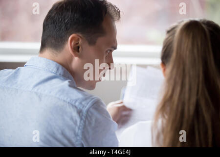 Back view image of thoughtful couple reading documents together Stock Photo