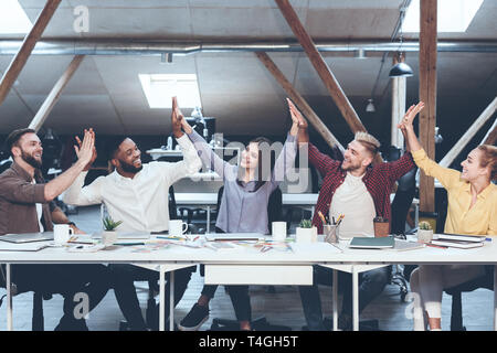 Teambuilding concept. Colleagues joining hands together, sitting in line Stock Photo