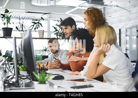Young team analyzing new information, looking at computer Stock Photo