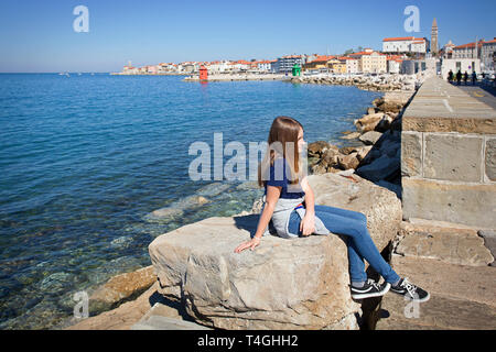 Teenage girl sitting on rocks by the sea Stock Photo