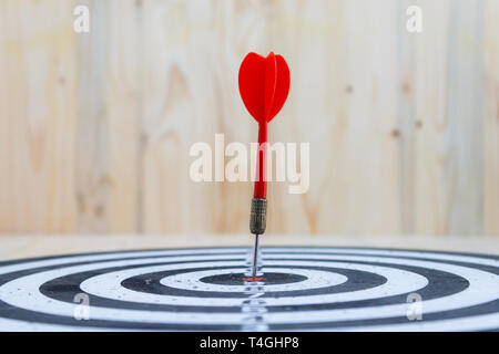 Winner Red dart arrow hit the center target of dartboard and yellow arrow loser metaphor marketing competition concept, on wood background Stock Photo