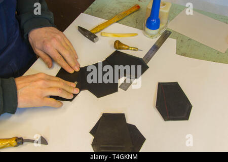 Master making leather wallet in the shape of coffin. Stock Photo