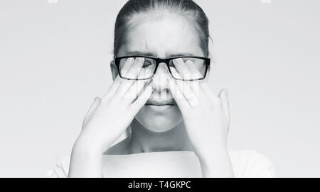 Young caucasian woman in glasses rubbing her eyes Stock Photo