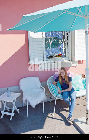 Girl on a chair, pink wall, shop exterior Stock Photo