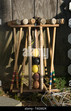 Old well-used Croquet Mallets in a rack, leaning against a wooden wall Stock Photo