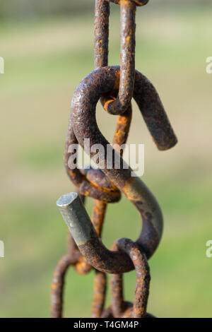 Old rusty chain, chain links, and large s-hook with a green bokeh background, close-up, Block Island, RI Stock Photo
