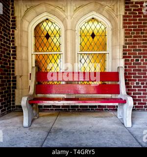 New Orleans, LA USA - 05/08/2018  -  Red Bench In Front of Stained Glass Windows at Loyola University Stock Photo