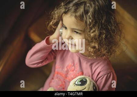 Girl, 3 years, portrait, sitting on the stairs with mobile phone, phoned, Germany Stock Photo