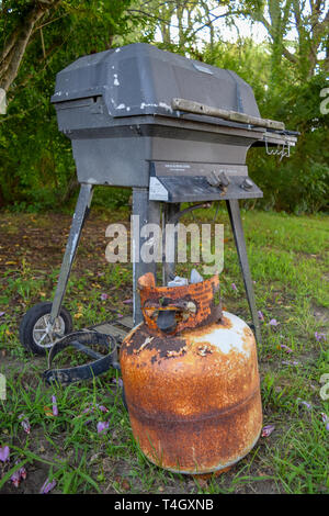 Old and very rusty propane canister and outdoor grill Stock Photo