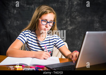 Bored teenage girl doing homework assignment at home Stock Photo