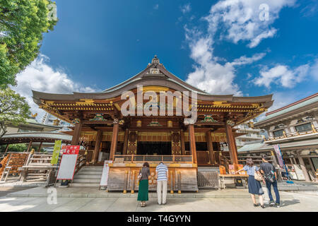 People praying at Honden (Main Hall) of Yushima Tenmangu - Yushima Tenjin. Shinto Shrine devoted to Tenjin, Kami of Learning, famous among scholars Stock Photo