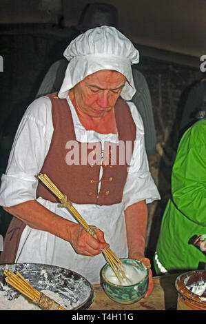 Tudor Woman in Kitchen Preparing Food on Table,  Reconstruction, Kentwell Hall Suffolk Stock Photo
